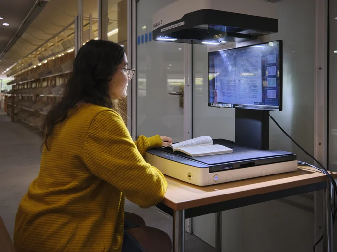 Studentin scannt ein Buch an einem Scanner in der Zentralbibliothek ein. 