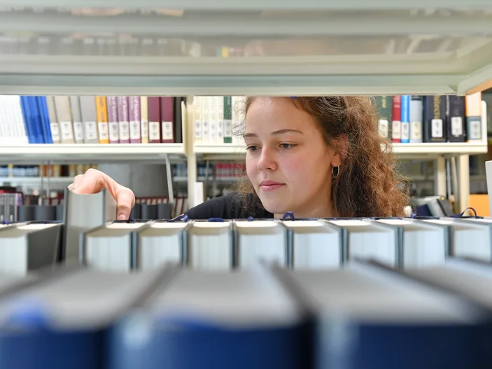 Eine junge Frau sortiert Bücher in ein Regal