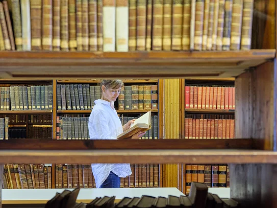 Blick in den Heynesaal Leserin im Heyne-Saal zwischen Regalen mit alten Büchern, Blick durch ein Bücherregal