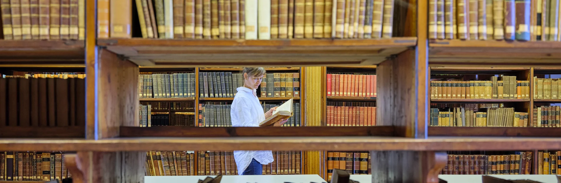 Blick in den Heynesaal Leserin im Heyne-Saal zwischen Regalen mit alten Büchern, Blick durch ein Bücherregal