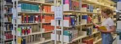 Studentin zieht ein Buch aus einem Regal im Lesesaal der Zentralbibliothek