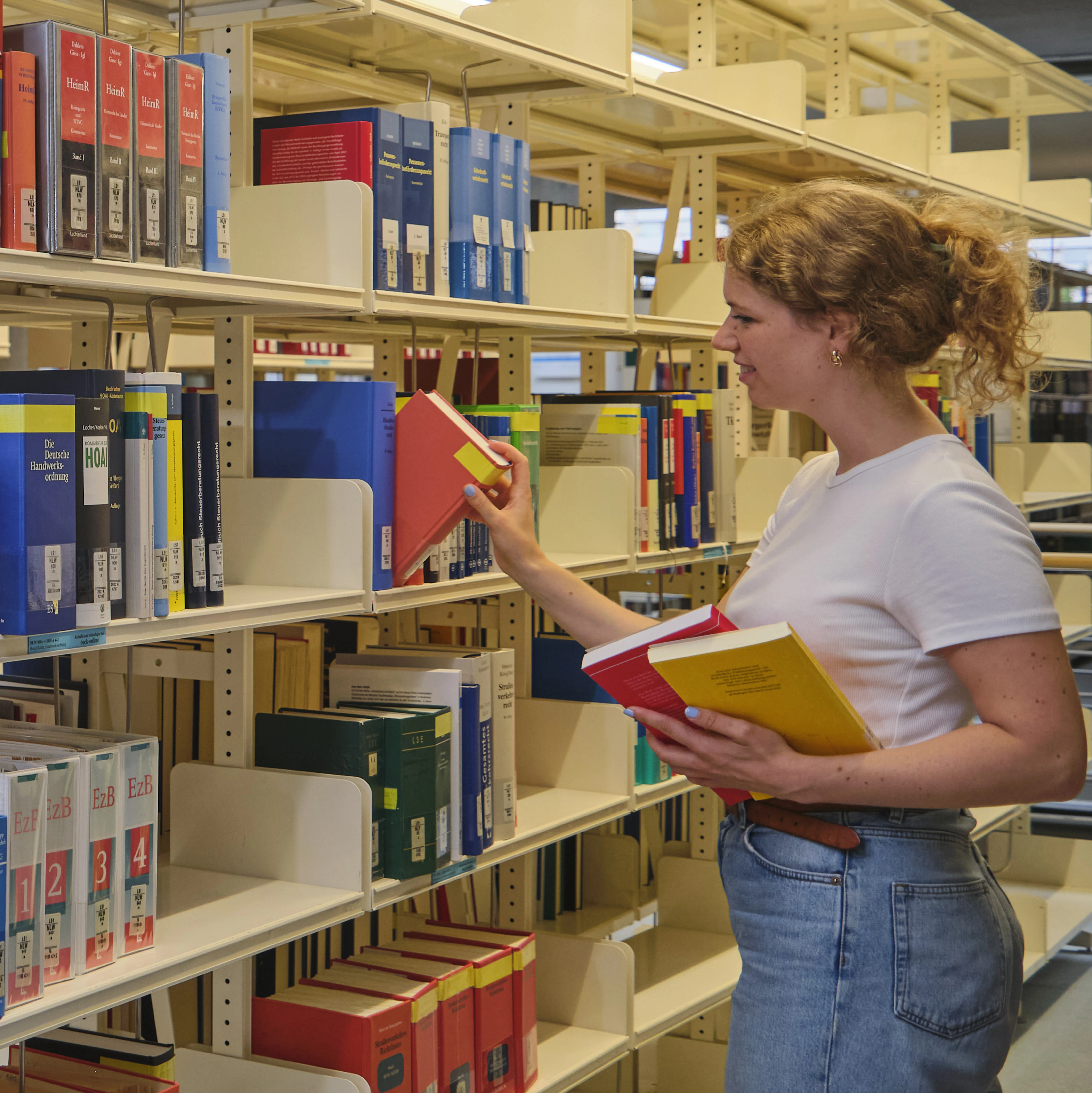 Studentin zieht ein Buch aus einem Regal im Lesesaal der Zentralbibliothek