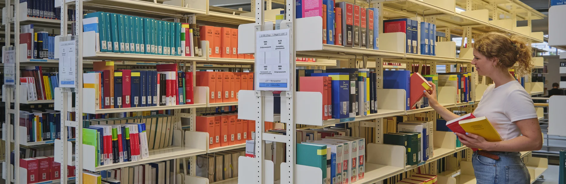 Studentin zieht ein Buch aus einem Regal im Lesesaal der Zentralbibliothek