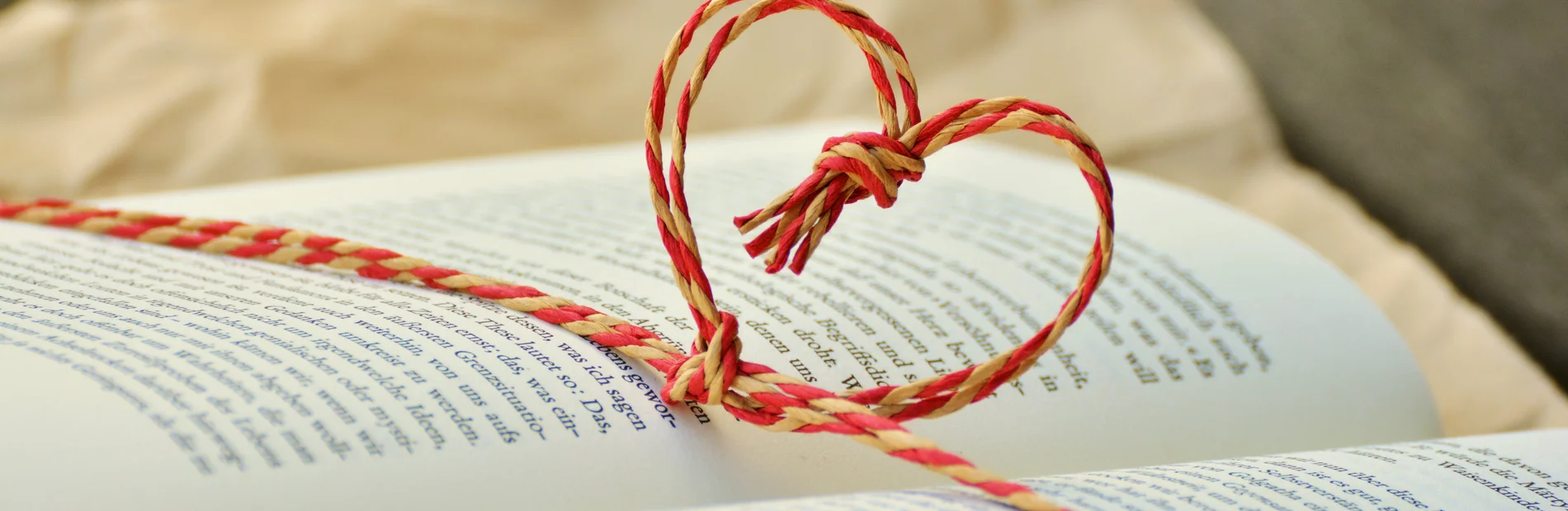 Ein Bindfaden in Herzform auf einem aufgeschlagenen Buch