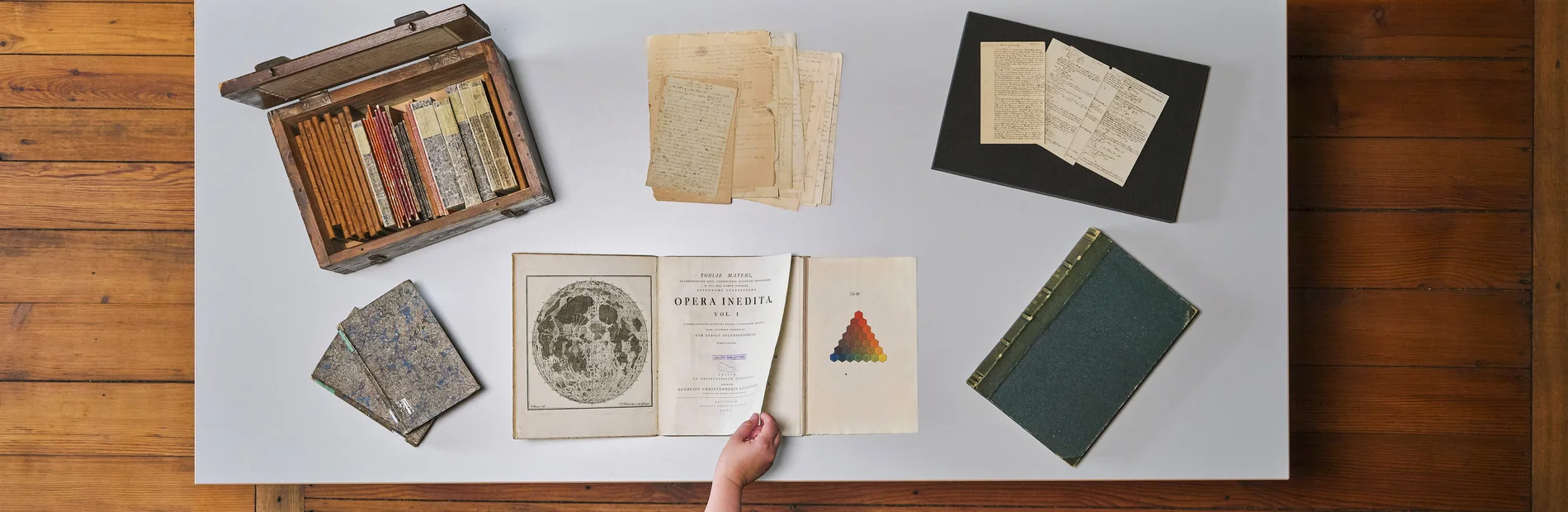 Historische Sammlungen der SUB Göttingen Tisch mit historischen Büchern und Archivmaterialien, eine Hand blättert in einem Buch