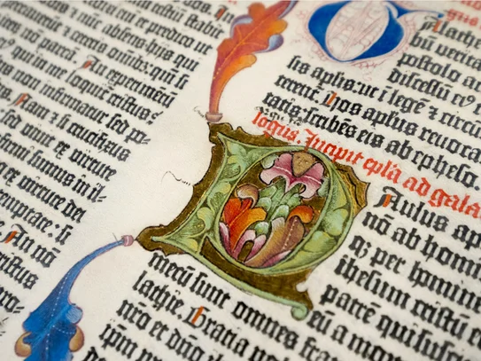 Initiale aus der Gutenbergbibel Ausschnitt eines gedruckten Texts aus der Bibel mit einer handgezeichneten Initiale mit Ranken