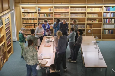 Einführung in die Benutzung von Altbeständen Ein Vortrag vor historischen Büchern, dem eine Gruppe von Menschen aufmerksam folgt
