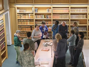 Einführung in die Benutzung von Altbeständen Ein Vortrag vor historischen Büchern, dem eine Gruppe von Menschen aufmerksam folgt