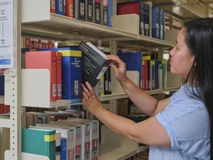Eine Studentin zieht ein Buch aus einem Regal im Lesesaal der Zentralbibliothek.