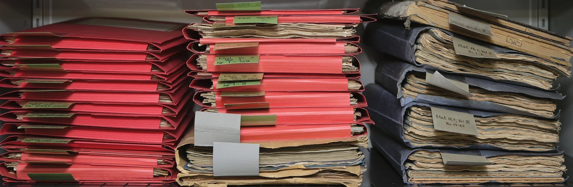 Blick ins Akademiemagazin Drei Stapel mit roten und blauen Mappen, die historische Materialien enthalten