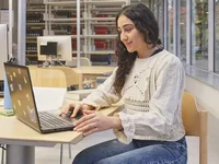 Person arbeitet in der Bibliothek am Laptop