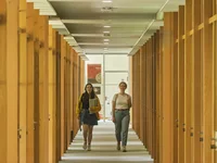 Zwei Studentinnen gehen einen Gang zwischen Arbeitskabinen in der Zentralbibliothek entlang