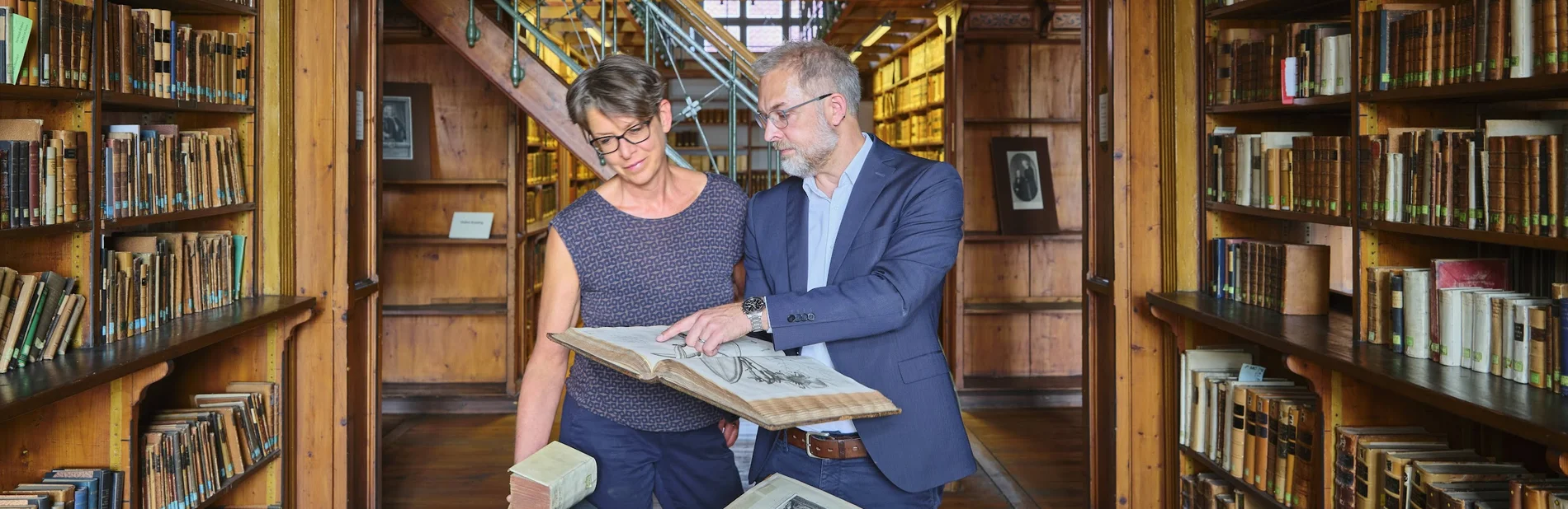 Beratung zu historischen Beständen an der SUB Göttingen Zwei Personen im historischen Bibliothekssaal, eine zeigt der anderen ein altes Buch