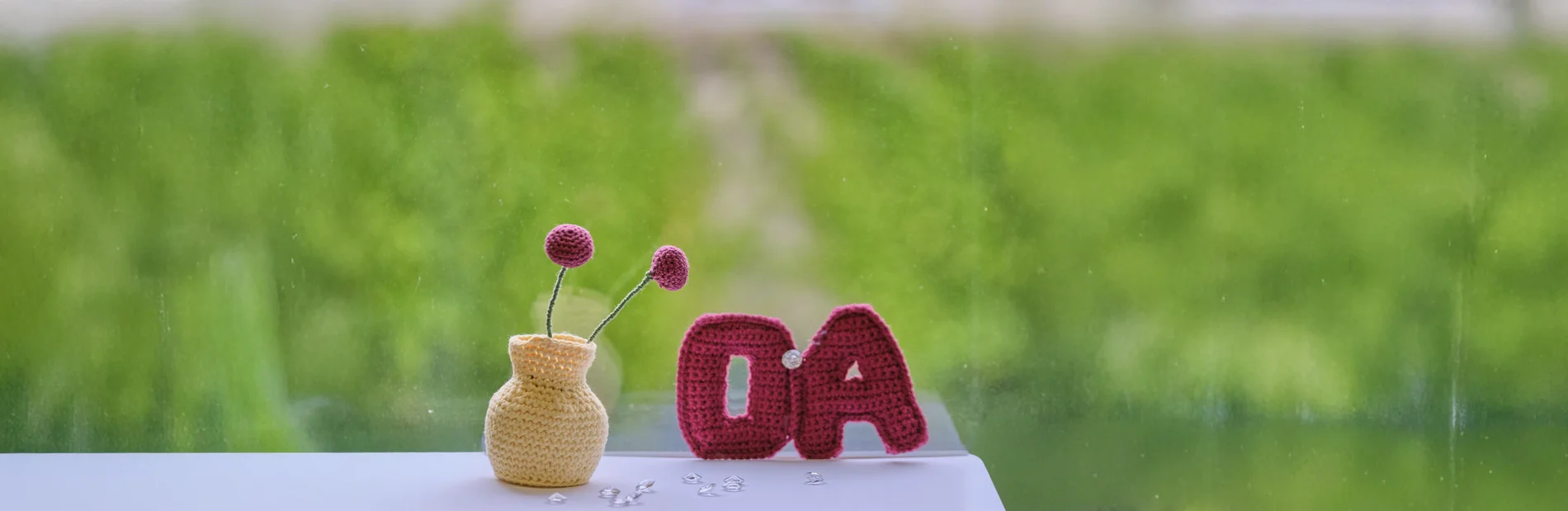 Gehäkeltes OA-Symbol und Blumenwase auf grünen Hintergrund