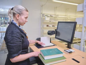 Studentin scannt ein Buch ein am Selbstverbucher in der Zentralbibliothek. 